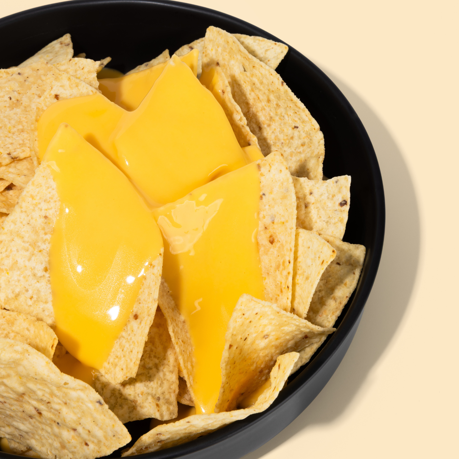 Tortilla chips with melted cheese on a black plate